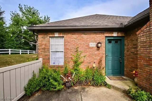 Property entrance with brick siding and a shingled roof
