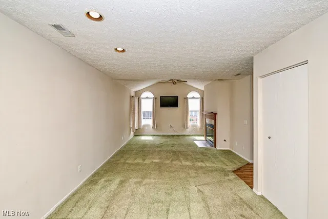 Hallway featuring carpet floors, vaulted ceiling, and a textured ceiling