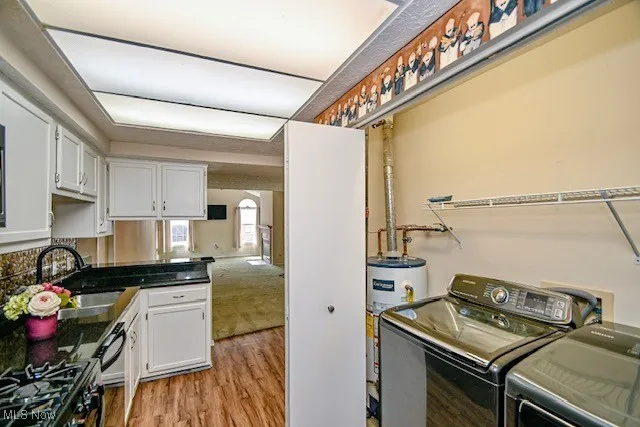 Washroom with washing machine and clothes dryer, gas water heater, and light wood-type flooring