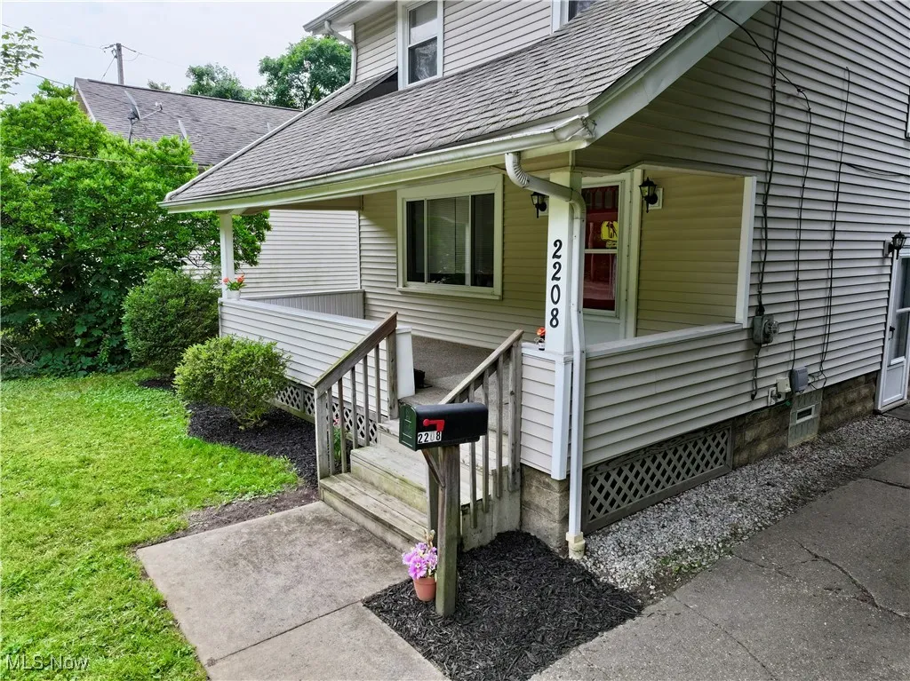 Entrance to property with roof with shingles, a yard, and a porch