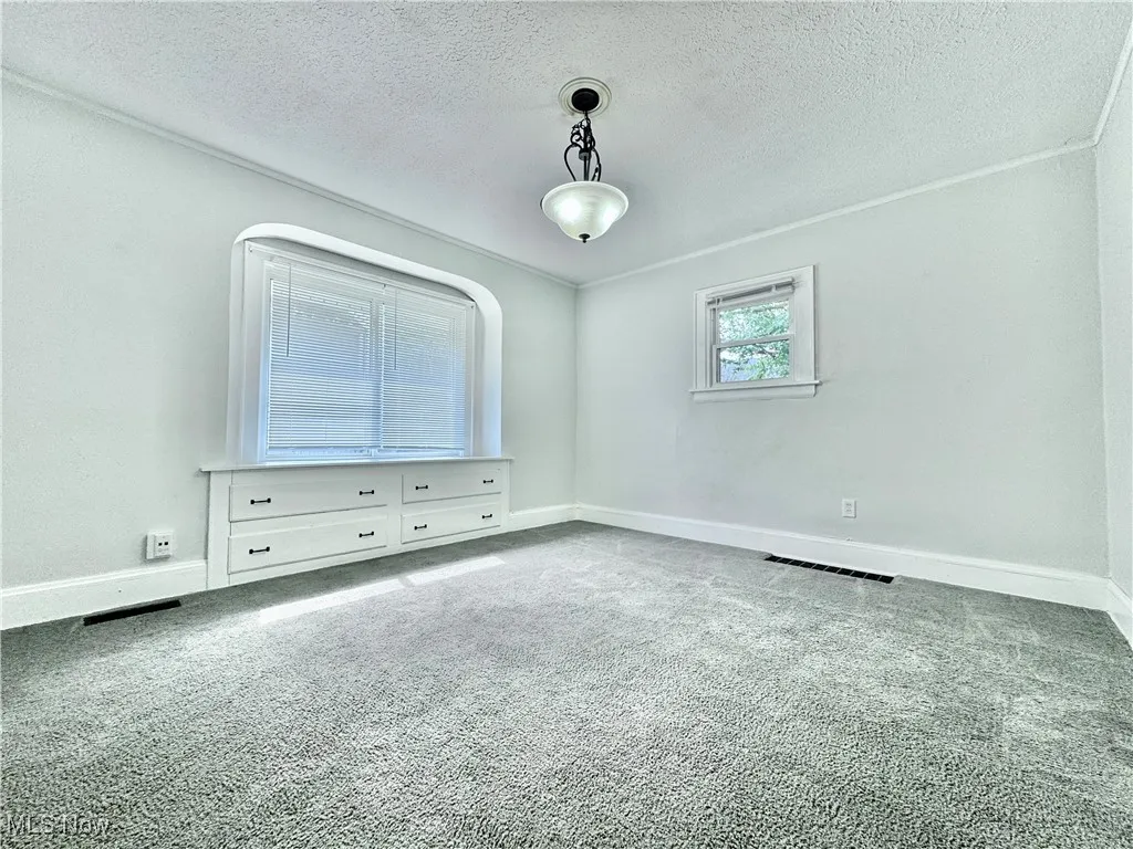 Empty room with carpet and a textured ceiling