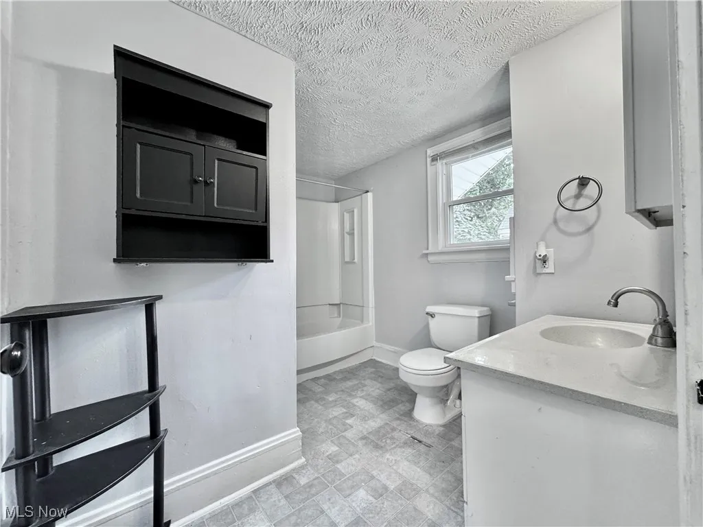 Bathroom with vanity, shower / washtub combination, and a textured ceiling