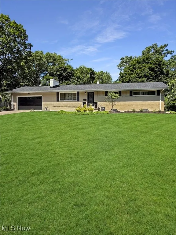Single story home featuring a front lawn, an attached garage, and driveway
