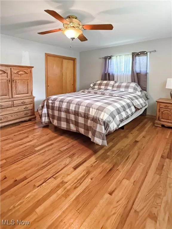 Bedroom featuring light wood-style floors, ceiling fan, and a closet