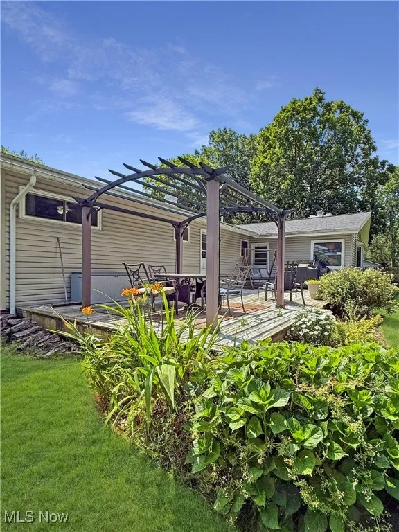 Back of house featuring a pergola, a yard, and a deck
