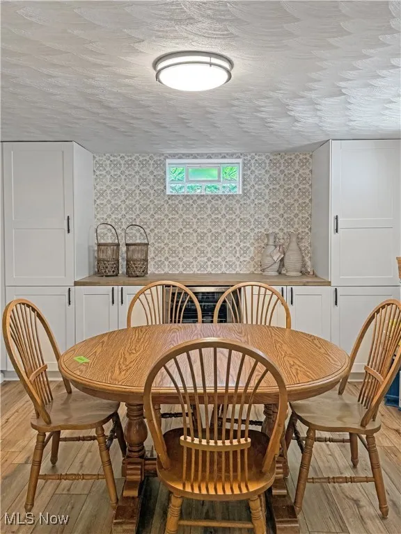 Dining room with wallpapered walls and light wood-style flooring