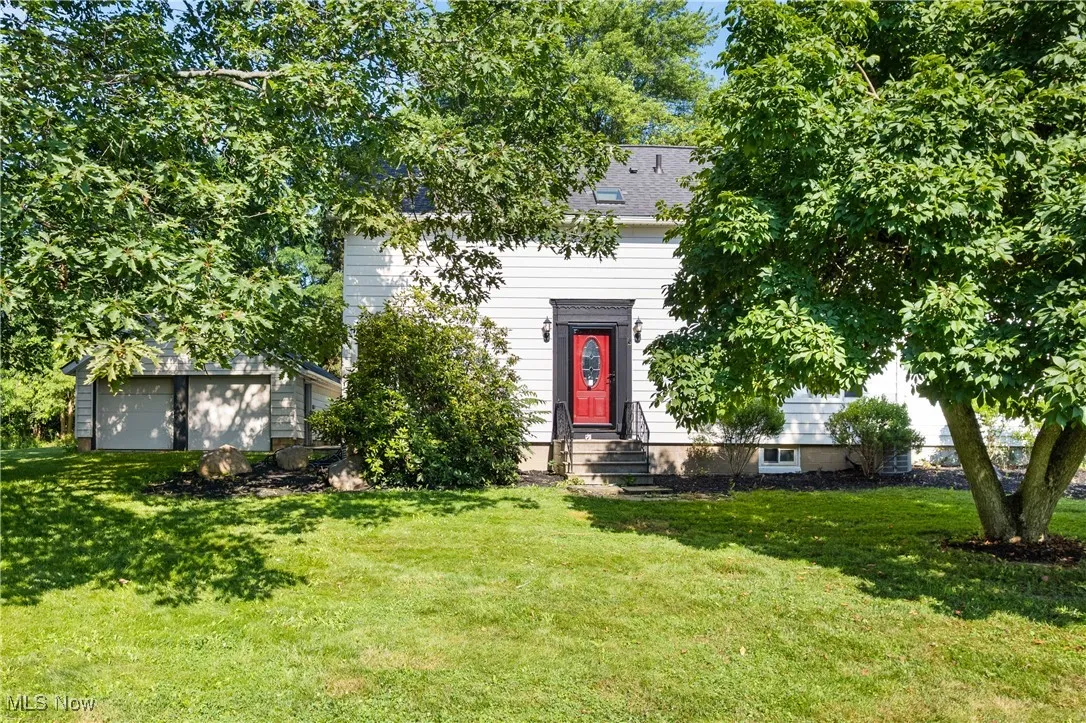 View of front of house with a front yard, a garage, an outdoor structure, and entry steps