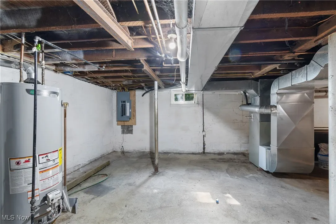 Below grade area with gas water heater, heating unit, and electric panel