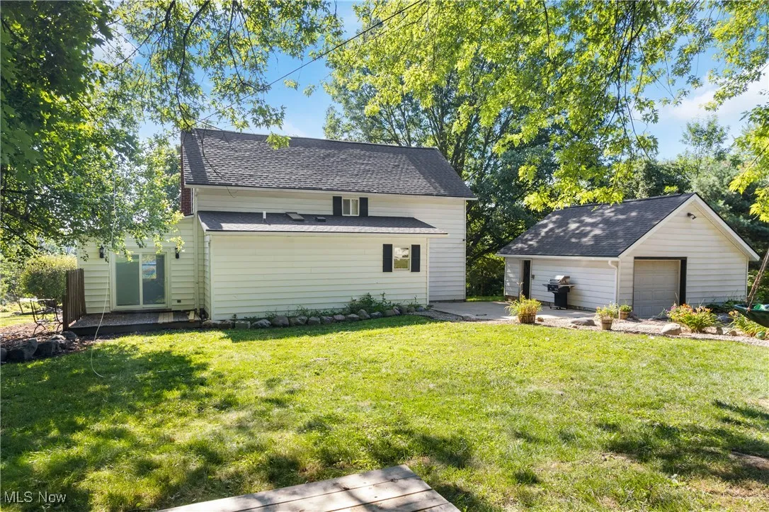 Back of house featuring a garage, an outdoor structure, and a yard