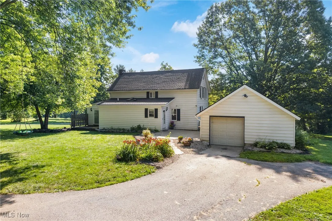 View of front facade featuring an outdoor structure, driveway, a front yard, and a 2 car detached garage