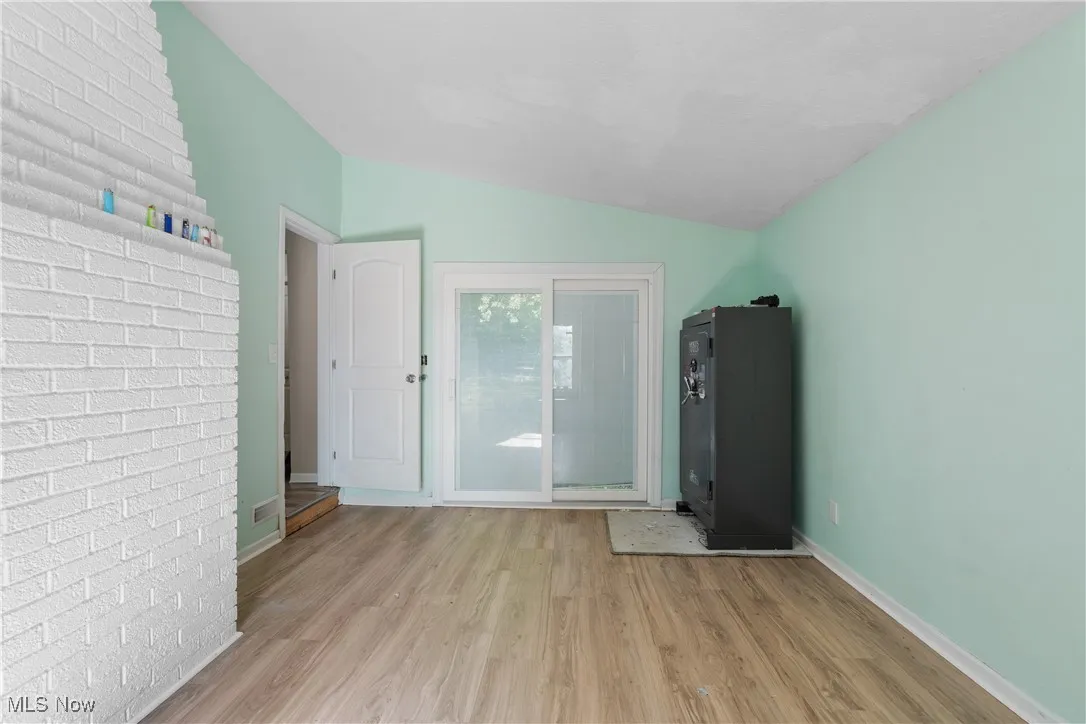 first floor bedroom with sliding door leading to back beck featuring lofted ceiling and vinyl finished floors