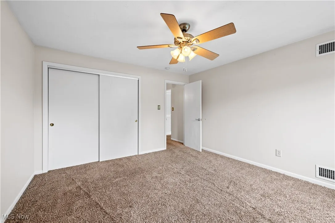 Unfurnished bedroom featuring carpet flooring, a closet, and a ceiling fan