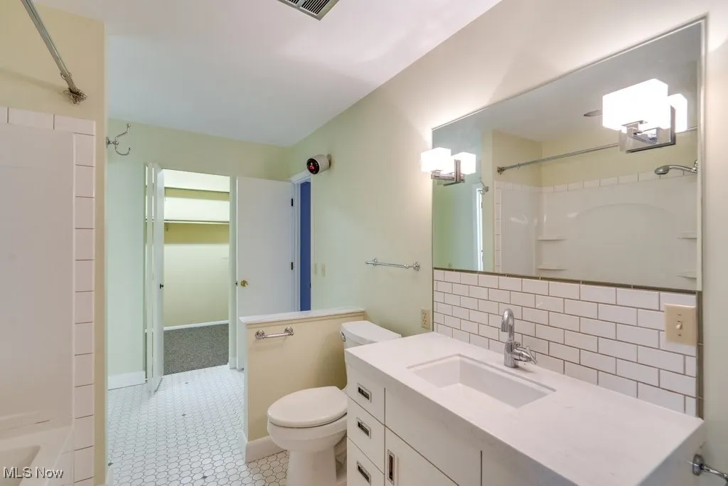 Bathroom with backsplash, vanity, and tub / shower combination