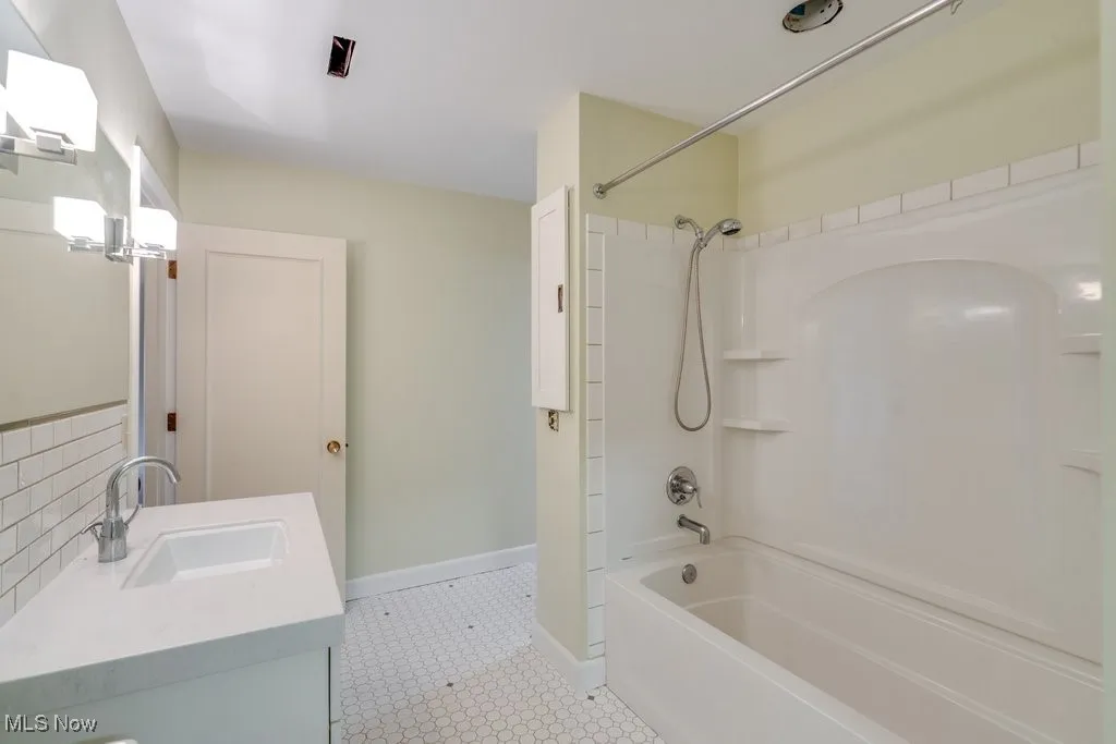 Full bathroom with bathing tub / shower combination, vanity, and backsplash