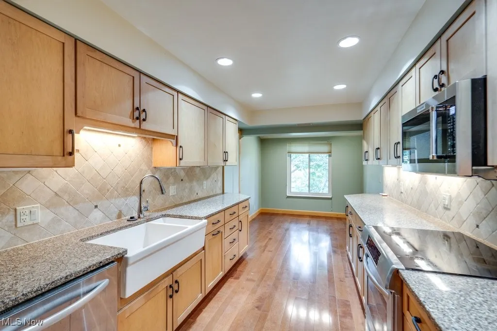 Kitchen with appliances with stainless steel finishes, light wood-style flooring, light stone countertops, recessed lighting, and decorative backsplash