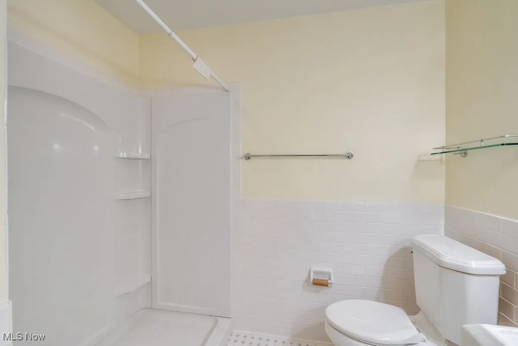 Full bathroom featuring tile walls, walk in shower, and a wainscoted wall