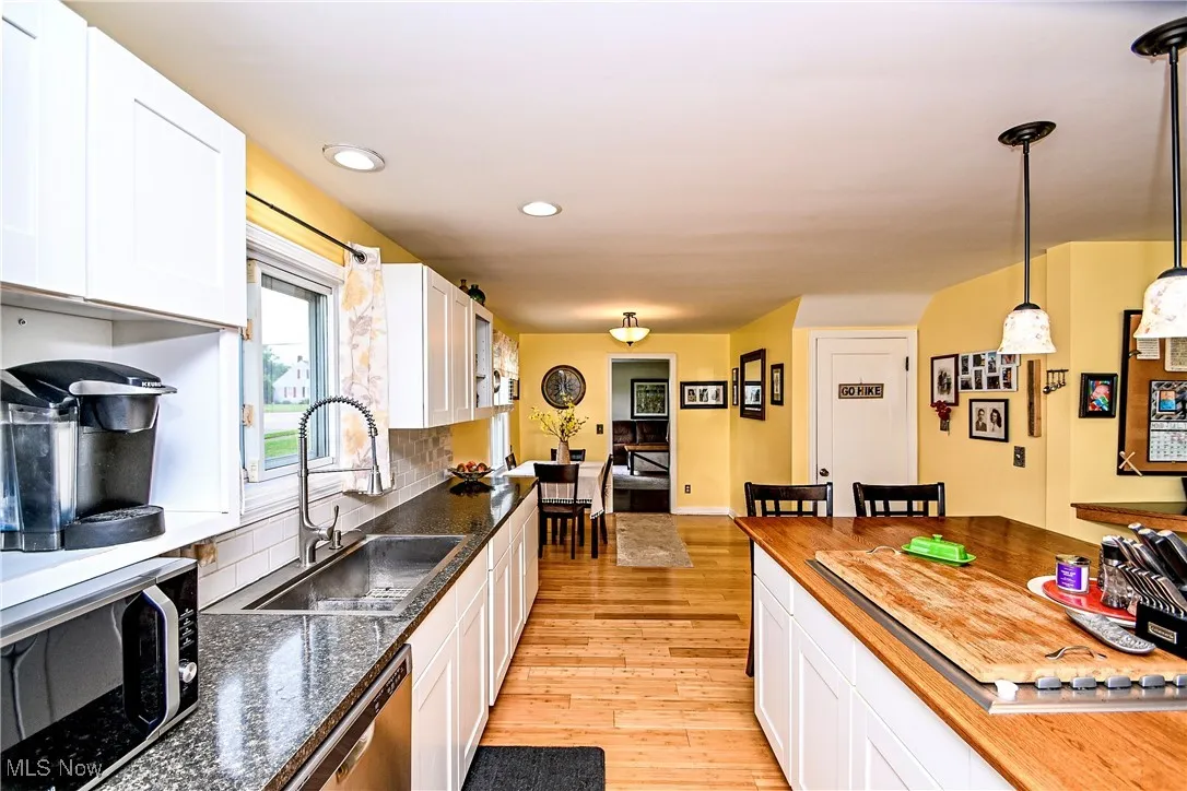 Kitchen featuring light wood-type flooring, stainless steel dishwasher, white cabinetry, butcher block countertops, and recessed lighting