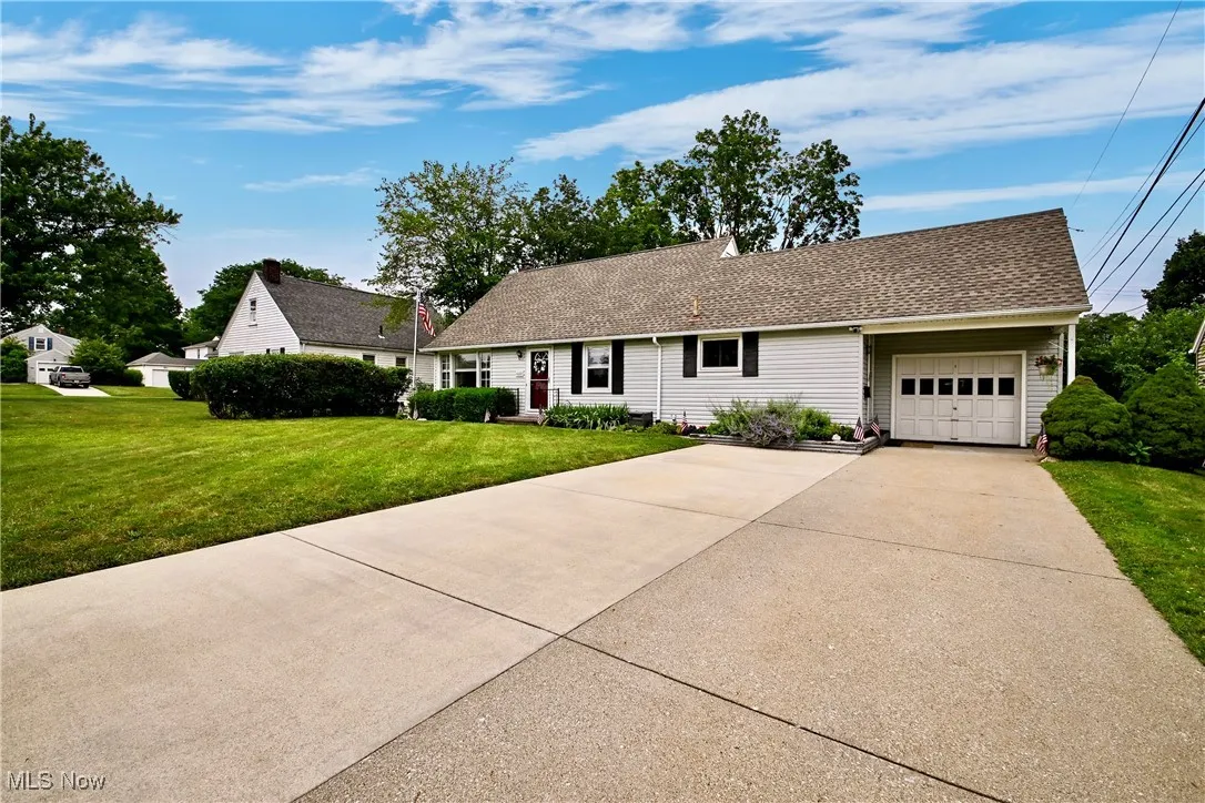 Bungalow home with concrete driveway, a front lawn, a garage, and roof with shingles