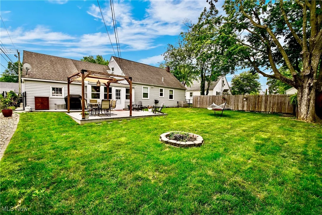 Rear view of house with a pergola, a fenced backyard, a patio, an outdoor fire pit, and roof with shingles