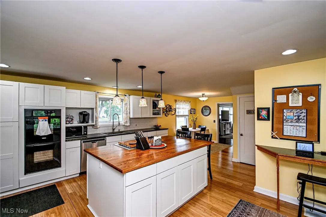 Kitchen featuring stainless steel dishwasher, wooden counters, light wood-style floors, white cabinetry, and recessed lighting