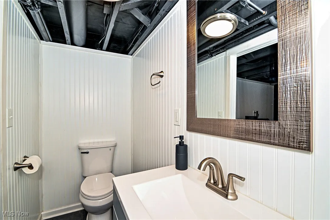 Half bathroom with toilet and vanity in basement