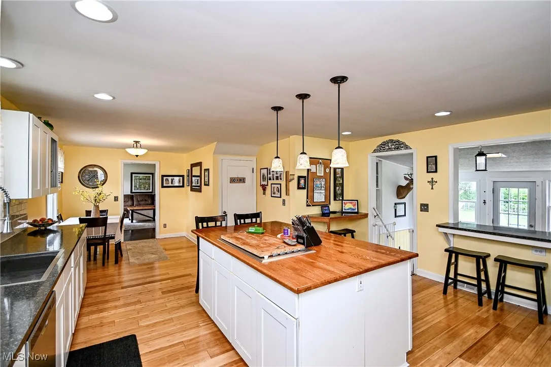 Kitchen featuring wood counter island, white cabinets, dishwasher, light wood-style floors, and recessed lighting