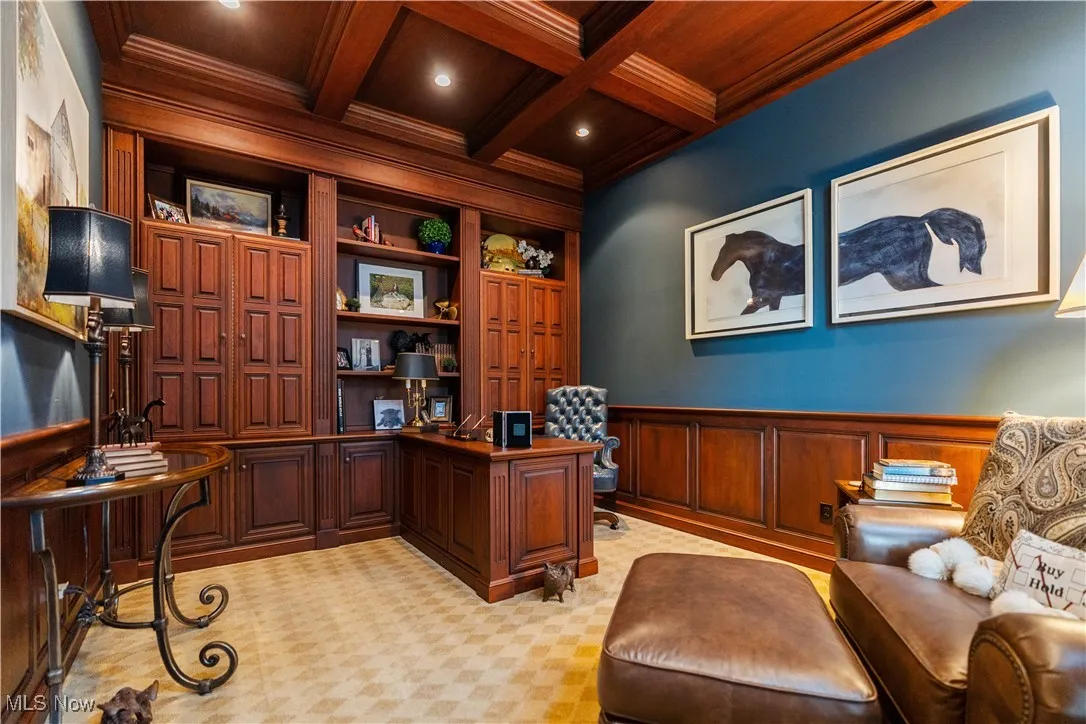 Office space with coffered ceiling, built in features, ornamental molding, light colored carpet, and a wooden ceiling with exposed beams