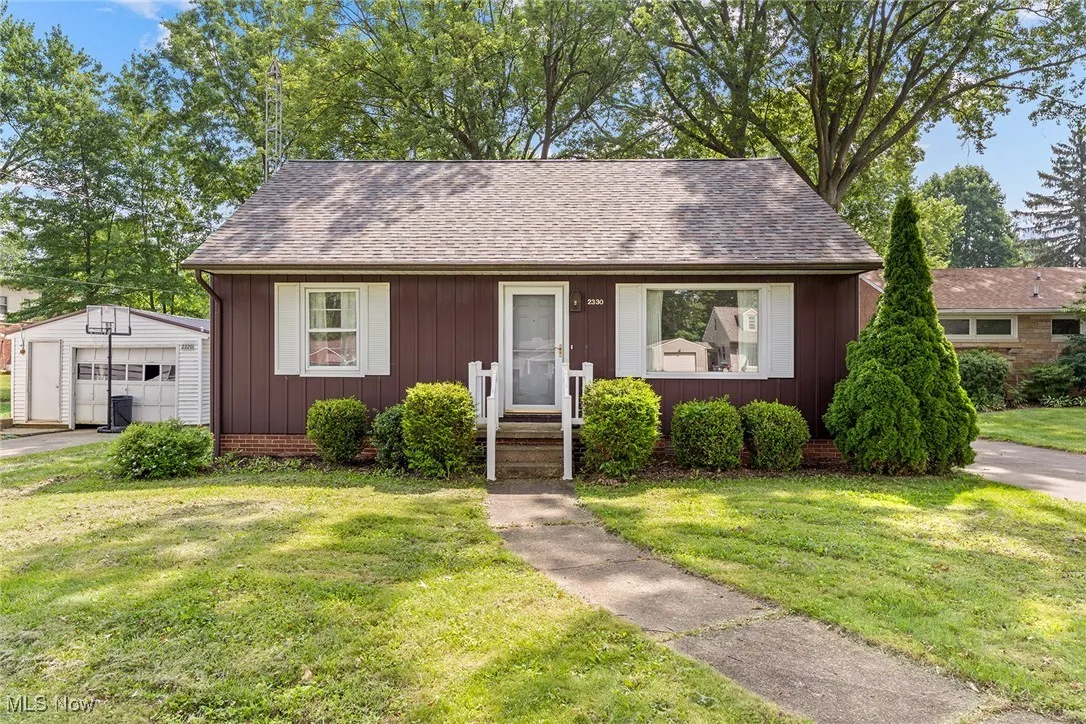 Bungalow-style home featuring an outbuilding, a front lawn, a detached garage, and roof with shingles