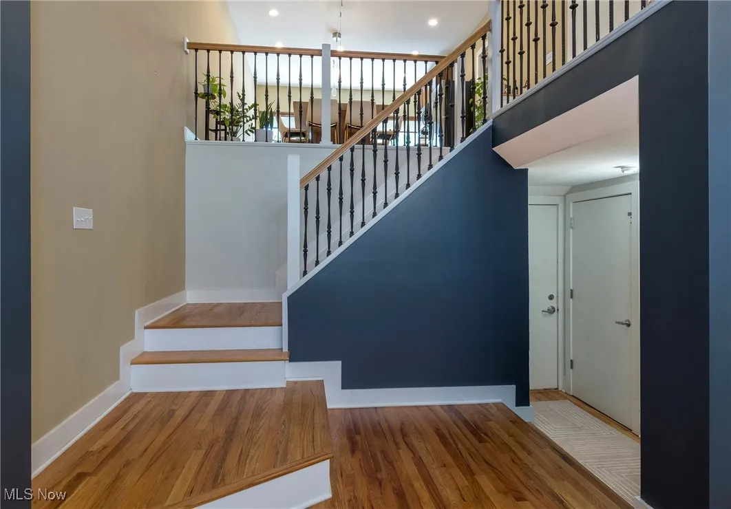 Staircase featuring wood finished floors, a high ceiling, recessed lighting, and plenty of natural light