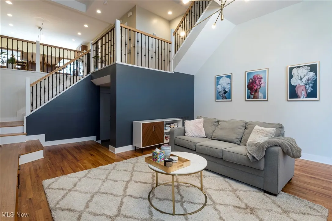 Living area featuring wood finished floors, a towering ceiling, stairway, and recessed lighting
