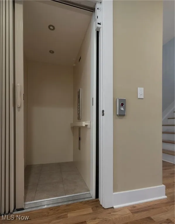 Corridor featuring elevator, wood finished floors, and stairway