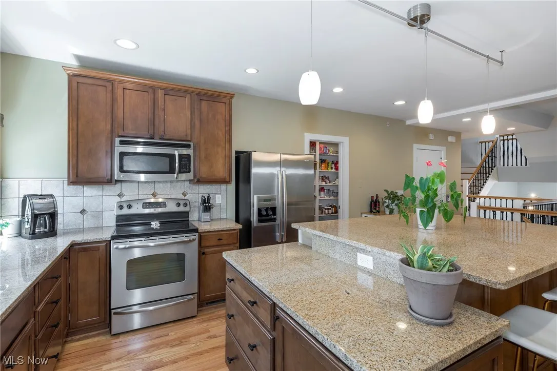 Kitchen with stainless steel appliances, hanging light fixtures, decorative backsplash, a breakfast bar, and recessed lighting
