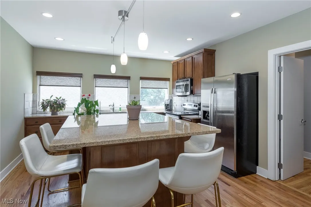 Kitchen with appliances with stainless steel finishes, decorative backsplash, light wood finished floors, a kitchen island, and recessed lighting