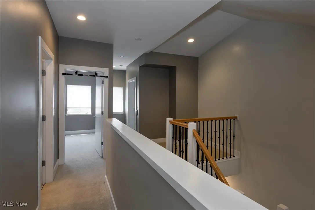 Hallway featuring an upstairs landing, light colored carpet, and recessed lighting