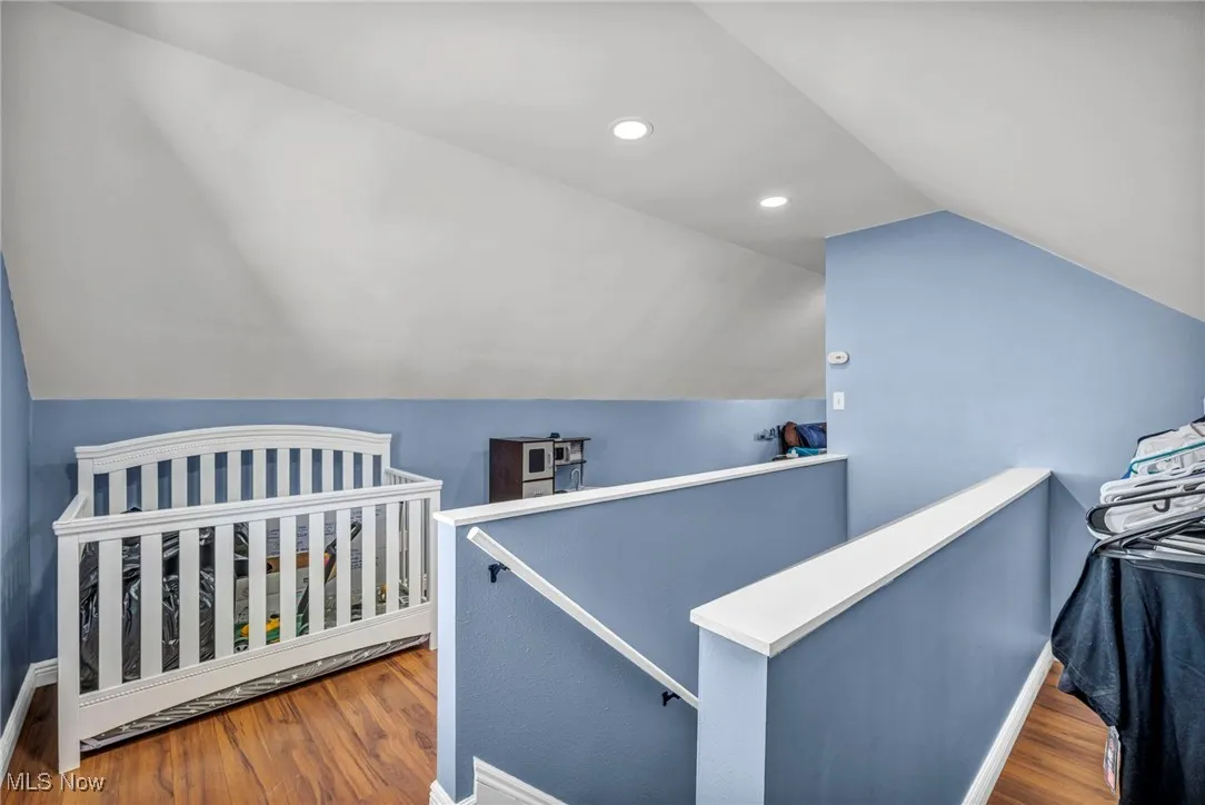 Bedroom with vaulted ceiling, wood finished floors, and recessed lighting