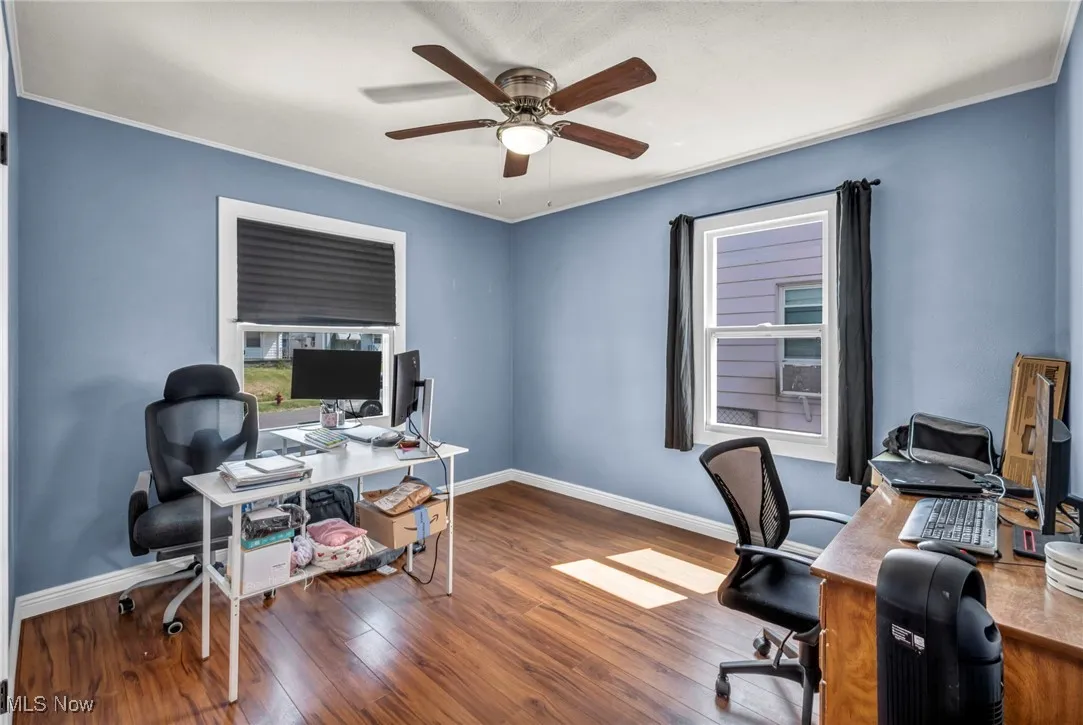 Office space with ceiling fan, wood finished floors, and crown molding