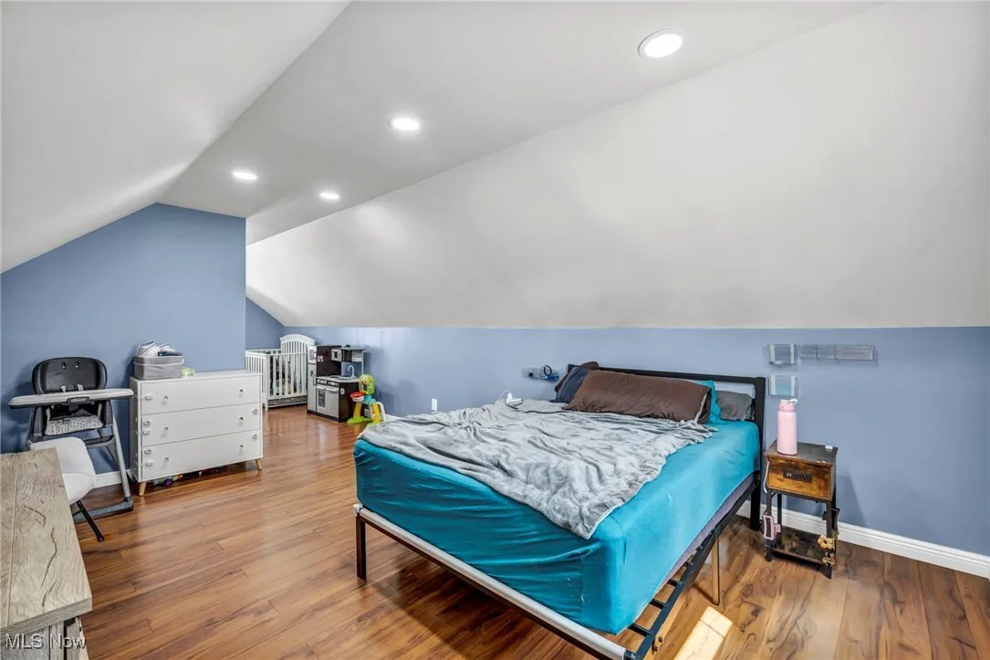 Bedroom featuring vaulted ceiling, wood finished floors, and recessed lighting
