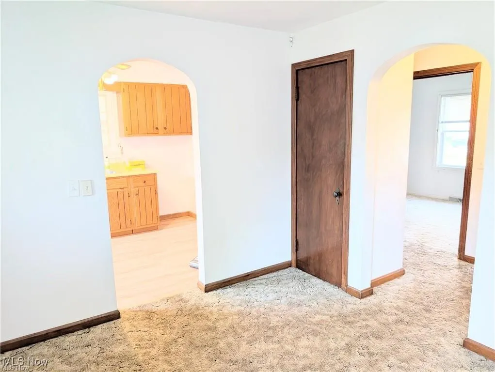 Room with arched walkways and light colored carpet