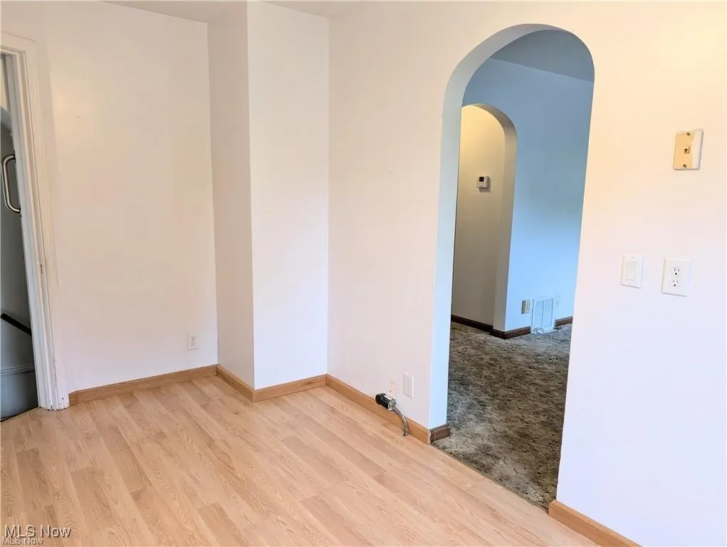 Unfurnished room with wood finished floors and arched walkways