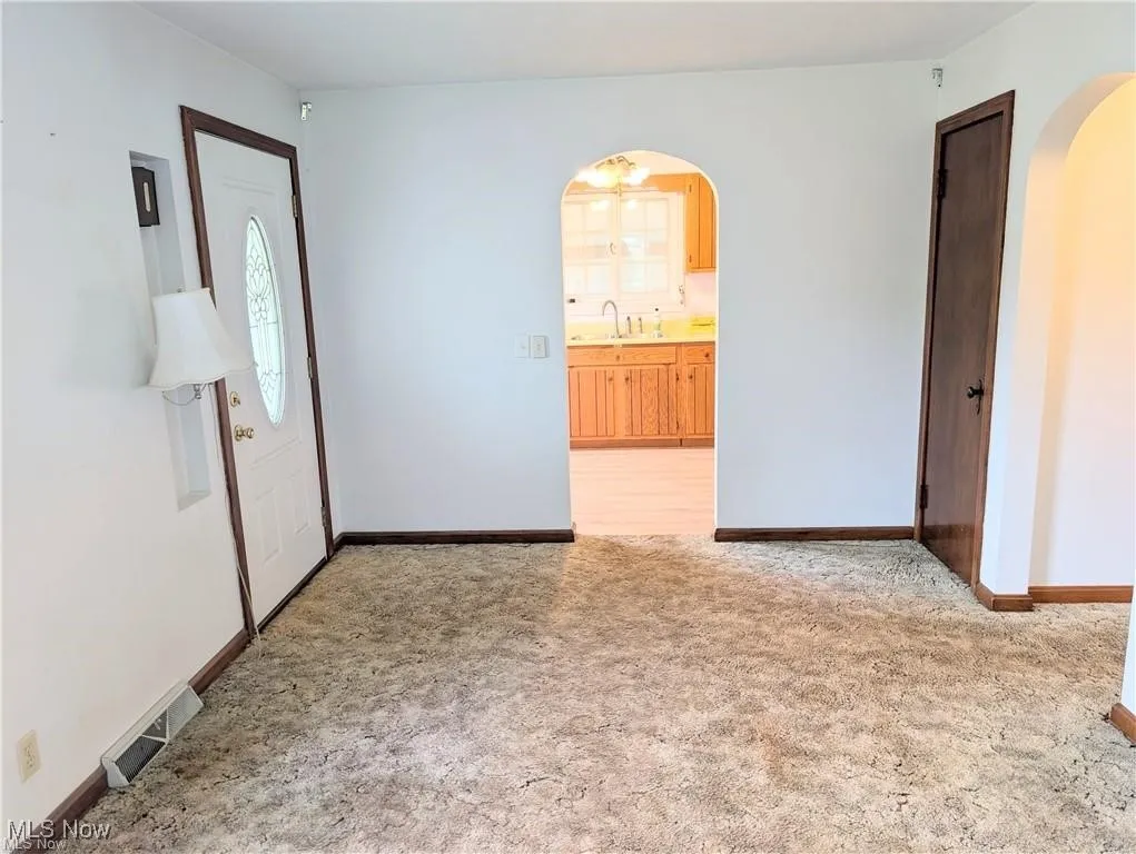 Room featuring arched walkways and light colored carpet