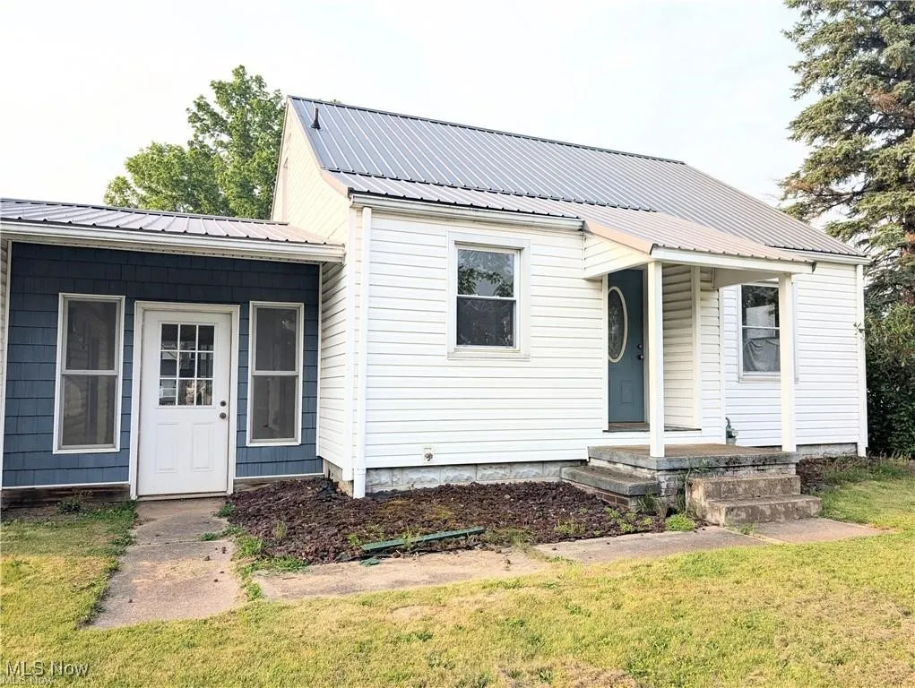 View of front facade featuring covered porch, a front yard, and a metal roof