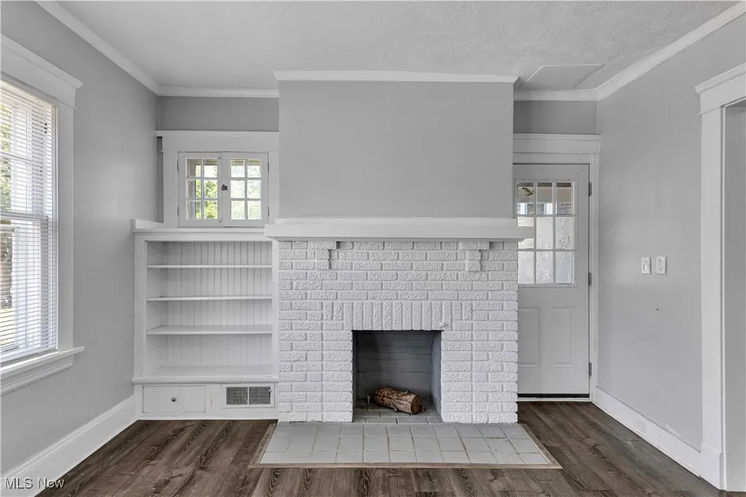 Unfurnished living room with a fireplace, wood finished floors, and crown molding