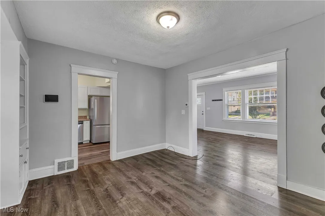 Unfurnished room with a textured ceiling and dark wood finished floors