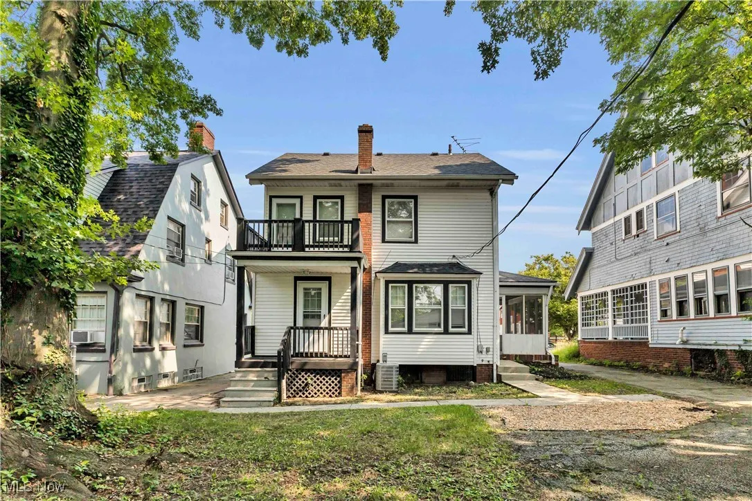 Back of property with a balcony, a chimney, a shingled roof, and cooling unit