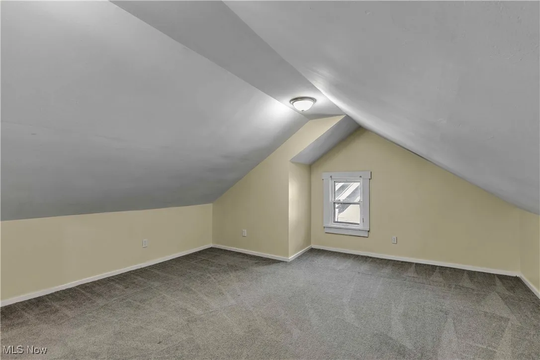 Additional living space with vaulted ceiling and carpet floors