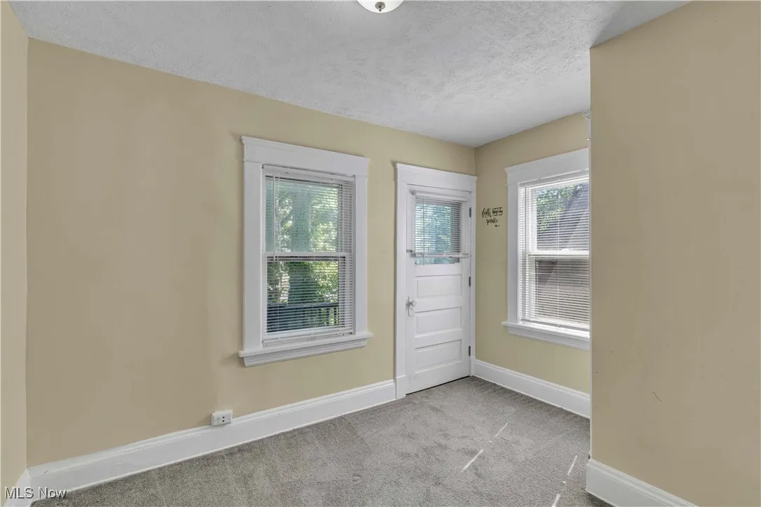 Doorway to outside with carpet floors, plenty of natural light, and a textured ceiling
