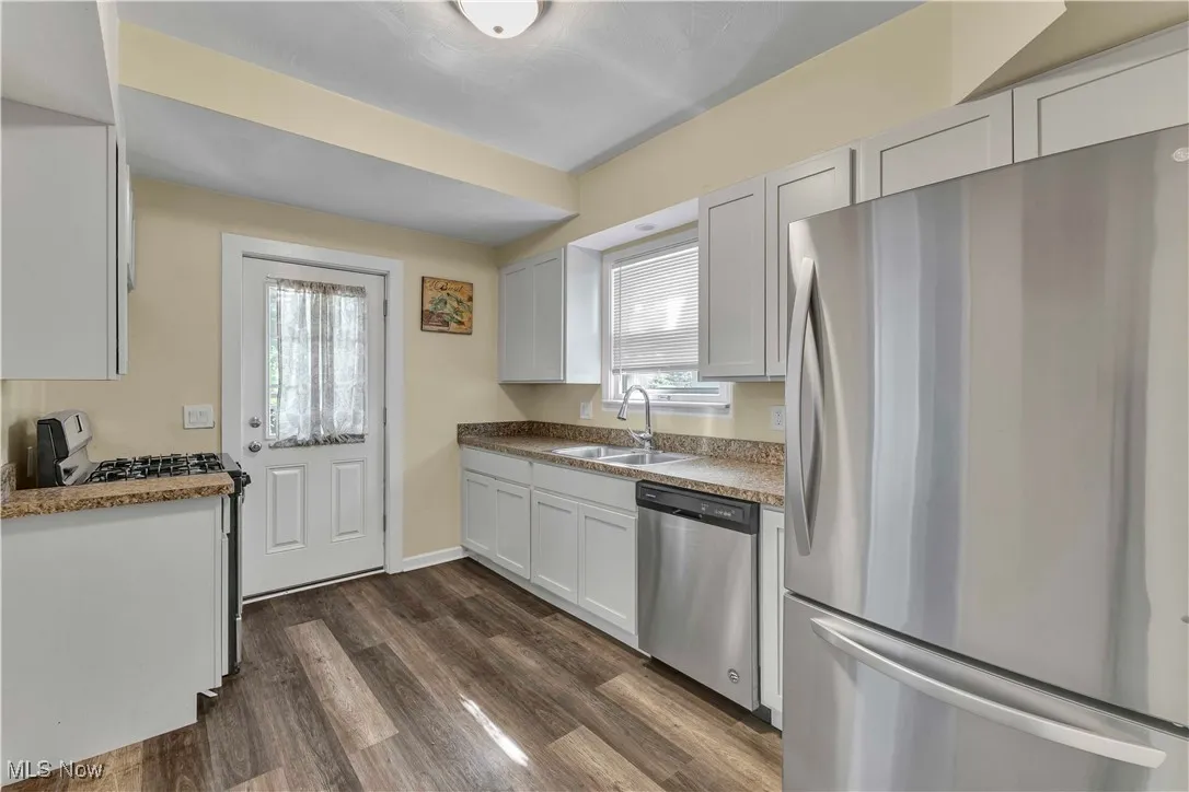 Kitchen with appliances with stainless steel finishes, dark wood-type flooring, and white cabinets