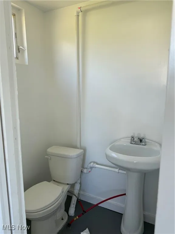 Half bathroom with toilet and baseboards