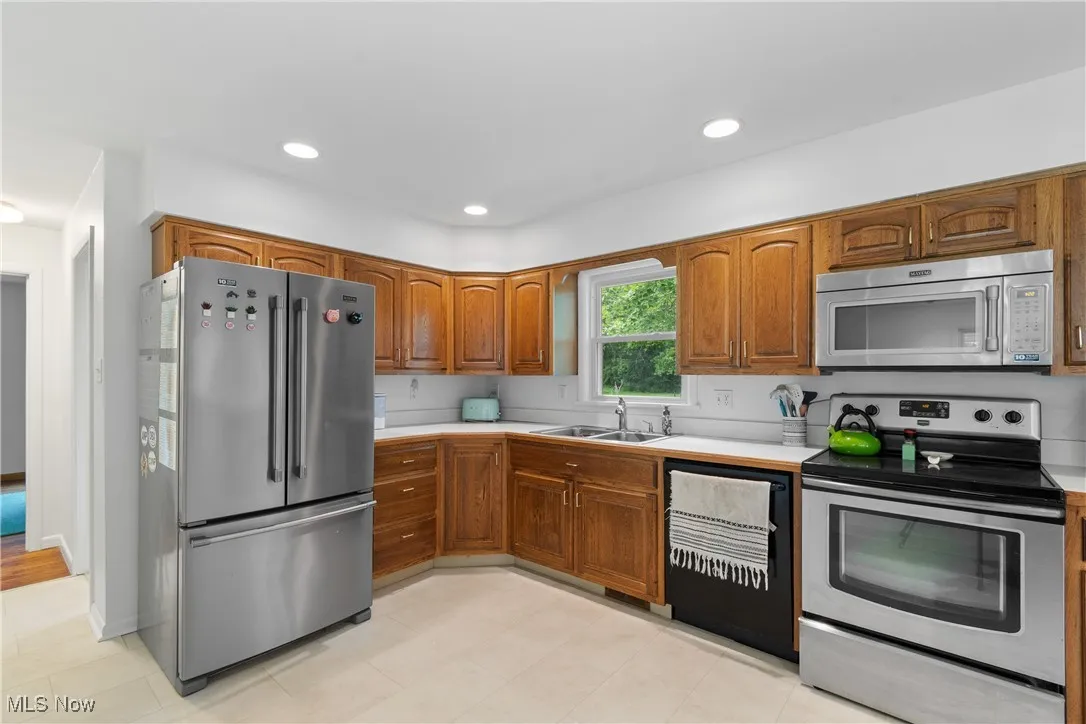Kitchen with appliances with stainless steel finishes, light countertops, brown cabinets, and recessed lighting