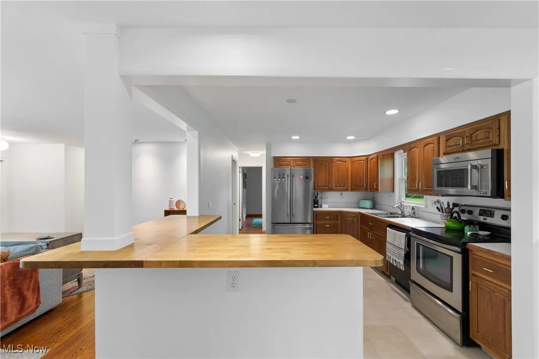 Kitchen featuring appliances with stainless steel finishes, butcher block counters, a peninsula, and recessed lighting